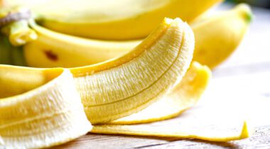 half pealed banana with bunch of bananas in background