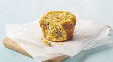 muffin shaped egg bites with bite taken out of it on wooden plate with parchment paper.