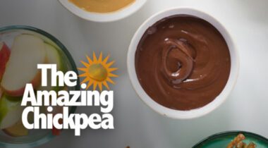 small white bowl of chocolate chickpea spread with small bowl of cut up apples