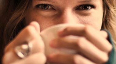 woman sipping mug, smiling with eyes