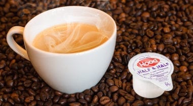 hot coffee and hood creamer with coffee beans background